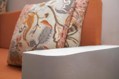 a white chair with a floral pillow on a table at Ghala House Apartment Moshi in Moshi