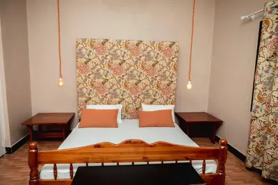 a bed with two pillows on it in a room at Ghala House Apartment Moshi in Moshi