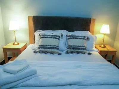 a large white bed with pillows and two lamps at ILBORU HAVEN HOMEs in Arusha