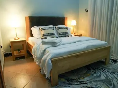 a bedroom with a large bed with two lamps on tables at ILBORU HAVEN HOMEs in Arusha