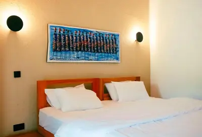 two beds with white sheets and a painting on the wall at Misitu Eco-Lodge in Karatu