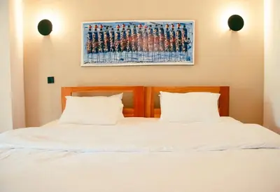 a bed with two white pillows and a painting on the wall at Misitu Eco-Lodge in Karatu