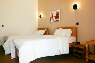 two beds in a hotel room with white sheets at Misitu Eco-Lodge in Karatu
