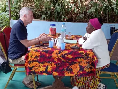 an older man and woman sitting at a table at Vanilla coffee farm lodge campsite in Arusha