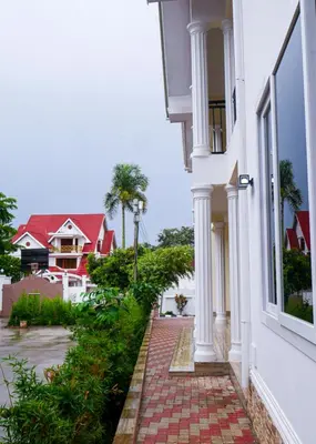 a white building with a brick walkway next to a window at VvEK B&B APARTMENT in Arusha
