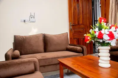 a living room with a couch and a table with a vase of flowers at VvEK B&B APARTMENT in Arusha