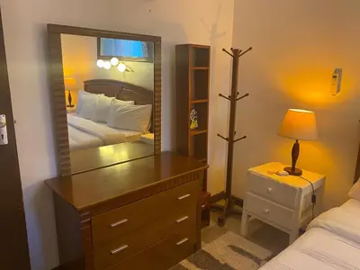 a bedroom with a mirror and a dresser with a bed at JDs Home in Arusha