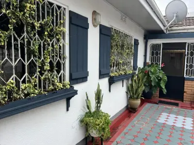 a house with blue shutters and plants on the front porch at JDs Home in Arusha