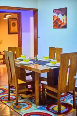 a wooden dining room table with bowls and chairs at Lavish Luxury Homes in Tengeru