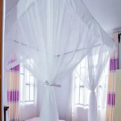 a bed with a white canopy and a window at Bethlehem home in Arusha