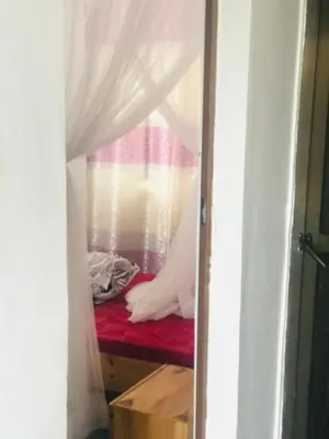 a room with a red bed with a curtain at Bethlehem home in Arusha