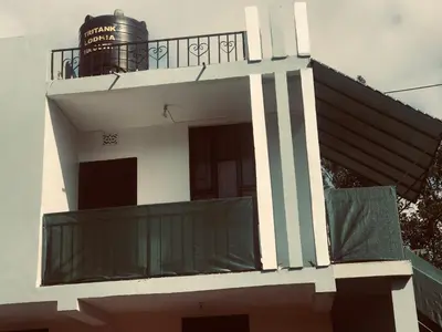 a white building with a balcony with a water tank at Bethlehem home in Arusha