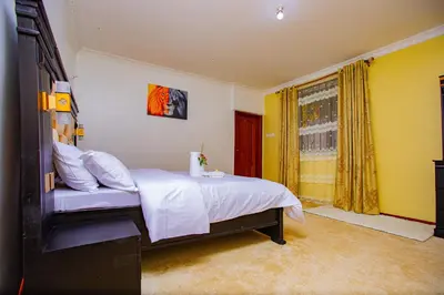 a bedroom with a bed with white sheets and a window at Divine Royal Residences in Arusha