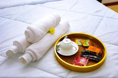 a towel and a tea set on a bed at Divine Royal Residences in Arusha