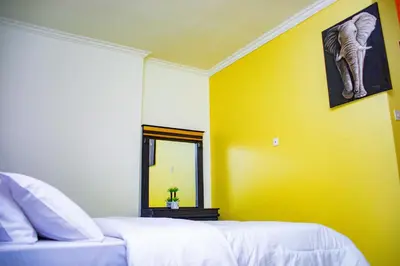 a bedroom with a bed and a yellow wall at Divine Royal Residences in Arusha