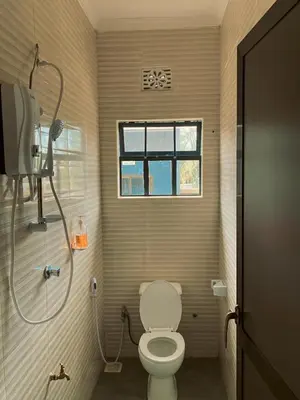 a bathroom with a toilet and a window and a shower at Kanyigo homes in Arusha