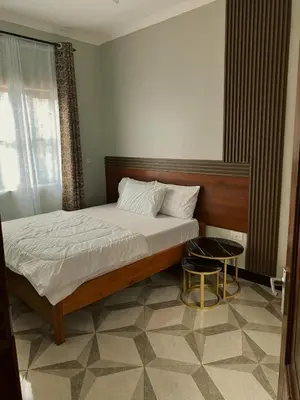 a bedroom with a bed and a table and a window at Kanyigo homes in Arusha