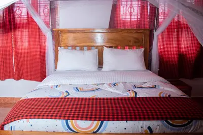 a bed with a red and white blanket and pillows at Meru Villa Arusha in Olmotoni