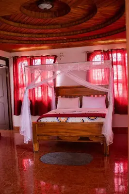 a bed with a canopy in a room with red curtains at Meru Villa Arusha in Olmotoni