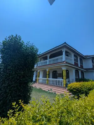 a large white house with yellow shutters at Meru Villa Arusha in Olmotoni