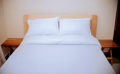 a bed with white sheets and pillows on it at Tembo Homestay in Arusha