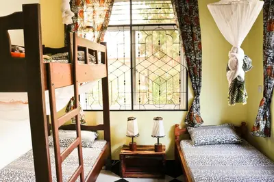 a room with two bunk beds and a window at Rafiki Backpackers & Guesthouse in Moshi