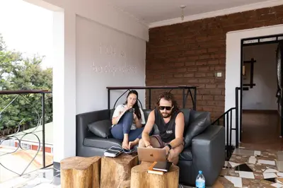 a man and a woman sitting on a couch with a laptop at Rafiki Backpackers & Guesthouse in Moshi