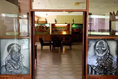 a dining room with a table and a window with portraits at Equator Hotel in Arusha