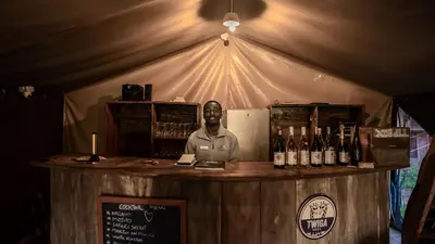 a man standing behind a bar with bottles of wine at Africa Safari South Serengeti Ndutu Camping in Sinoni