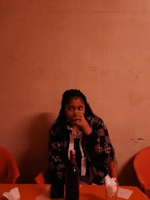 a woman sitting at a table with a bottle of wine at Last fantasy ndoto ya mwisho in Arusha