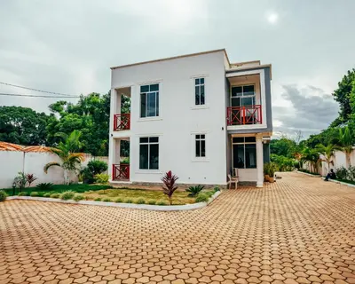 a white house with a brick driveway at Shanti Apartments in Uru