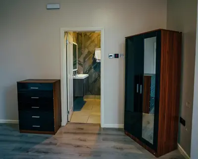 a bathroom with a dresser and a mirror at Shanti Apartments in Uru