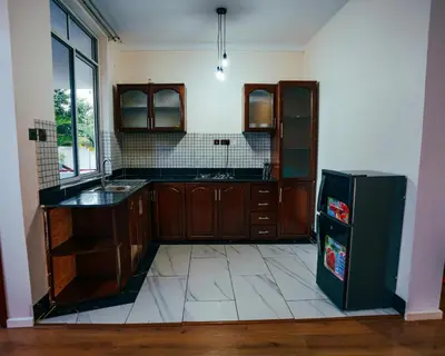 a kitchen with wooden cabinets and a black refrigerator at Shanti Apartments in Uru