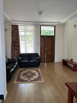 a living room with a black leather couch and a table at Shanti Apartments in Uru