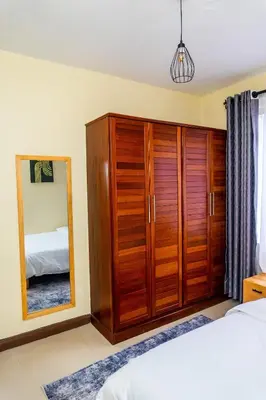 a bedroom with a wooden wardrobe and a mirror at Timeless Escape in Arusha
