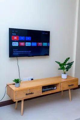 a television on a wall with a wooden entertainment center at Timeless Escape in Arusha