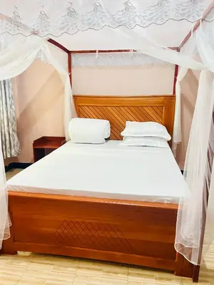 a bed with white sheets and a canopy at Sunset Inn Lodge in Arusha