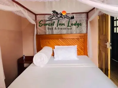 a bed in a small room with a sign on it at Sunset Inn Lodge in Arusha