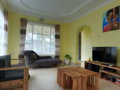 a living room with a tv and a couch and a coffee table at Sofa So Good Backpackers' Nest in Arusha