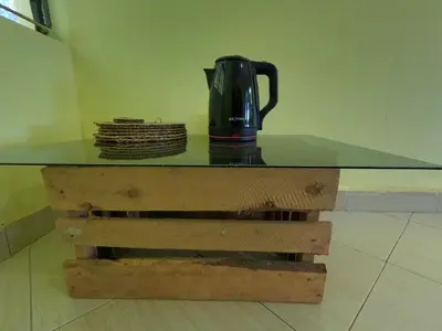 a glass table with a coffee pot on top of a wooden bench at Sofa So Good Backpackers' Nest in Arusha