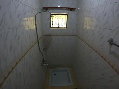 a small bathroom with a toilet and a window at Sofa So Good Backpackers' Nest in Arusha
