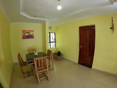 a room with a table and chairs and a door at Sofa So Good Backpackers' Nest in Arusha