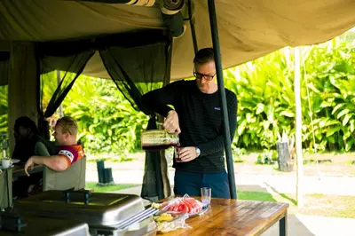 a man standing under a tent preparing food at Kibo View Farm Lodge in Shiri