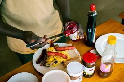 a person cutting a plate of food on a table at Kibo View Farm Lodge in Shiri