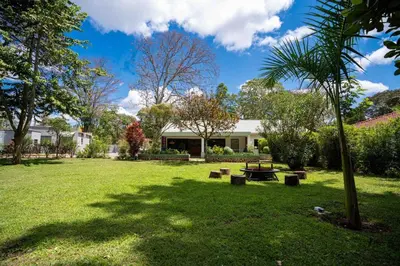 a park with a picnic table and benches in the grass at The Green House in Arusha