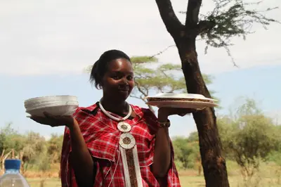 a woman holding two plates in her hands at Kili View Maasai Lodge in Longido