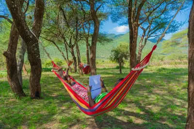 a person laying in a hammock with a book at Kili View Maasai Lodge in Longido