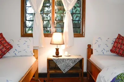 a room with two beds and a table with a lamp at Ethiopian restaurant and lodge in Arusha