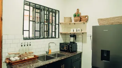 a kitchen with a sink and a refrigerator at Hatua Dahlia Home in Arusha
