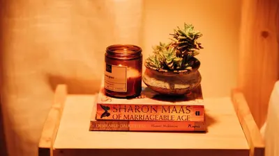 a book and a jar on a table with a plant at Hatua Dahlia Home in Arusha